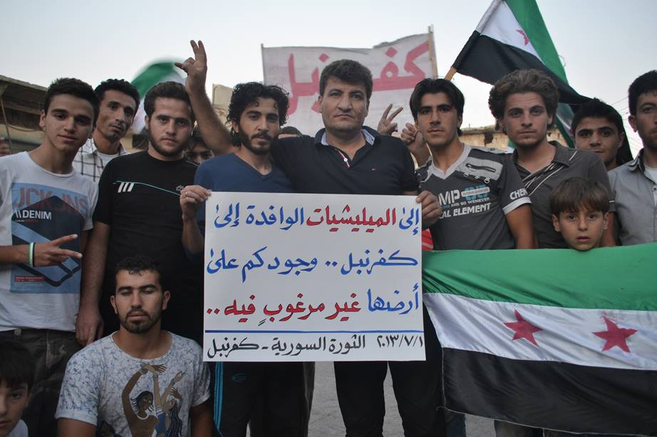 Raed Fares stands with Kafranbel residents holding banner
